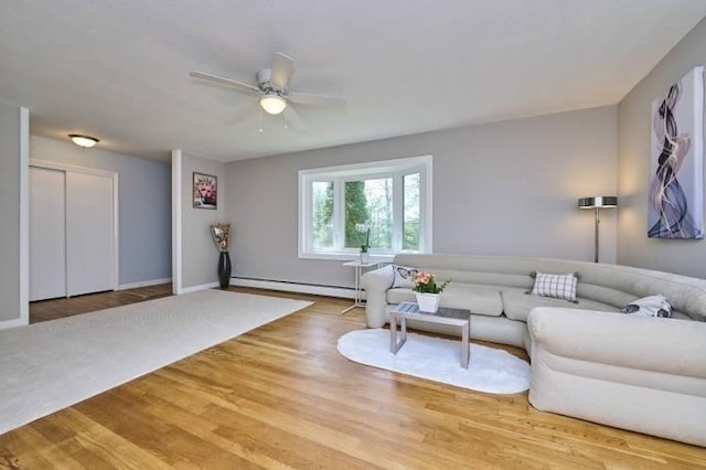 living room featuring a baseboard radiator, light wood-type flooring, ceiling fan, and baseboards
