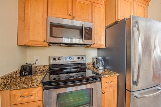 kitchen featuring dark stone counters and appliances with stainless steel finishes