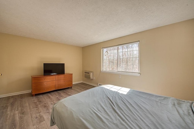 bedroom with a textured ceiling, baseboards, and wood finished floors