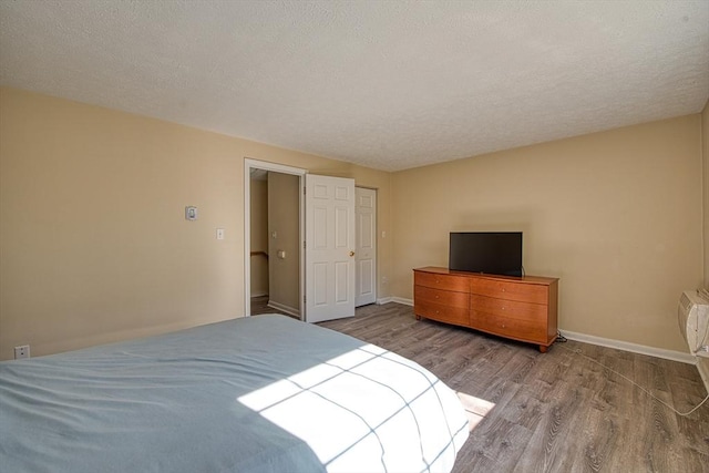 bedroom featuring a textured ceiling, baseboards, and wood finished floors