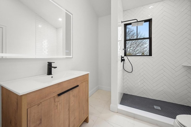 bathroom featuring vanity, a tile shower, toilet, and marble finish floor