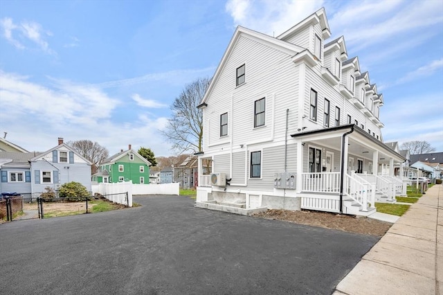 view of home's exterior with a porch, fence, and a residential view