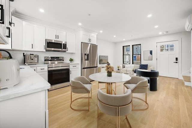 kitchen with backsplash, appliances with stainless steel finishes, light wood-style floors, recessed lighting, and white cabinetry