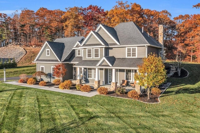 rear view of property with a chimney, a porch, and a yard