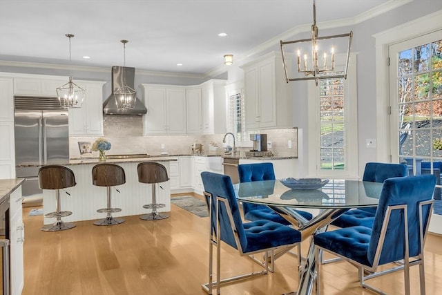 dining room with an inviting chandelier, crown molding, light wood-style flooring, and recessed lighting