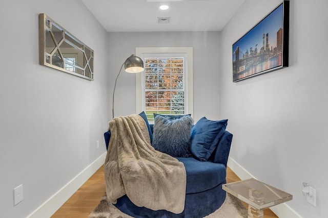 living area featuring visible vents, wood finished floors, and baseboards