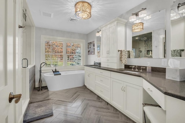 bathroom with a freestanding bath, a shower stall, vanity, visible vents, and a notable chandelier