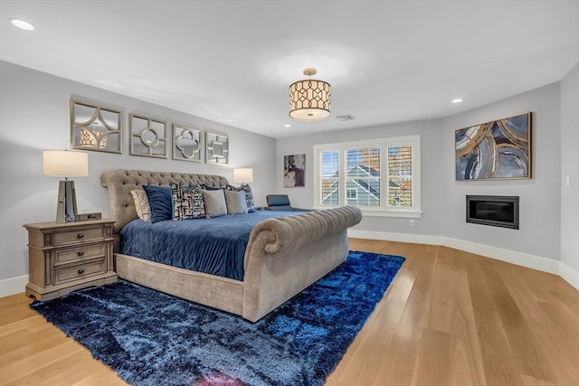 bedroom with wood finished floors, recessed lighting, visible vents, and baseboards