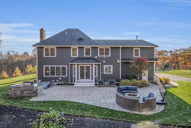 back of property featuring a lawn, an outdoor fire pit, a chimney, and a patio area