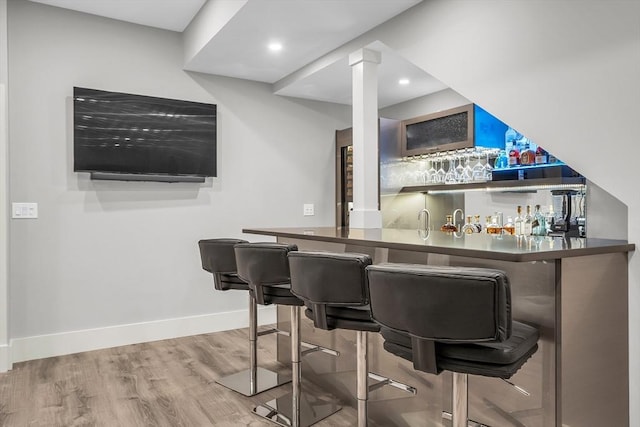 bar with recessed lighting, wet bar, wood finished floors, and baseboards