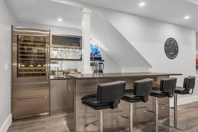 bar featuring recessed lighting, light wood finished floors, wet bar, and baseboards