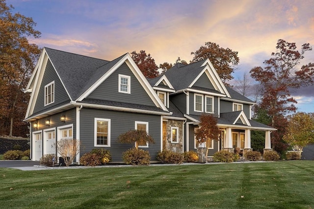 view of front of house with covered porch, aphalt driveway, a lawn, and an attached garage