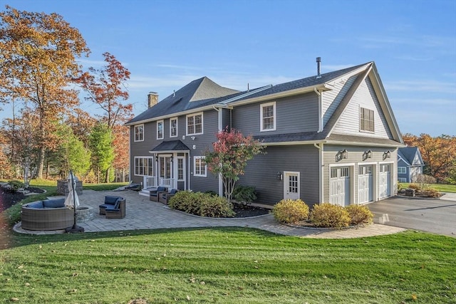 back of house with a garage, a patio, driveway, and a lawn