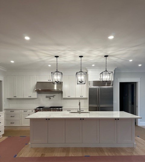 kitchen featuring pendant lighting, sink, stainless steel appliances, and a kitchen island with sink