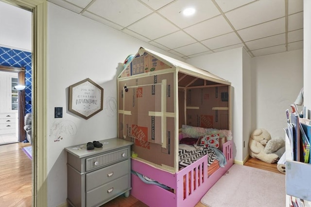 bedroom with a drop ceiling and wood finished floors