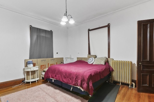 bedroom featuring a notable chandelier, radiator, and wood finished floors