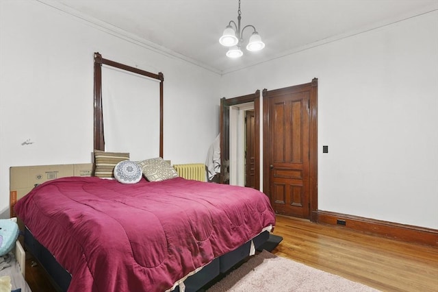 bedroom with crown molding, an inviting chandelier, and wood finished floors