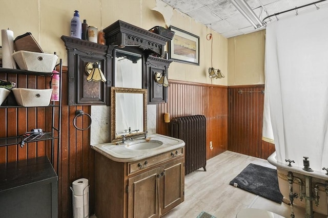 bathroom featuring vanity, wooden walls, radiator heating unit, and a wainscoted wall