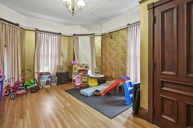 playroom featuring wood-type flooring and a notable chandelier