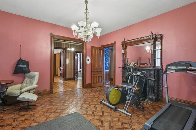 workout area with a notable chandelier and baseboards