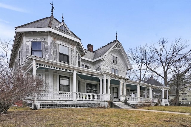 victorian house with a chimney, covered porch, and a front yard