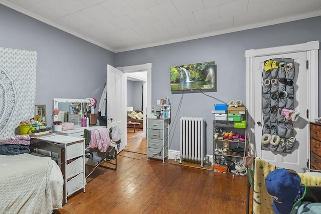 bedroom featuring radiator, crown molding, baseboards, and hardwood / wood-style floors