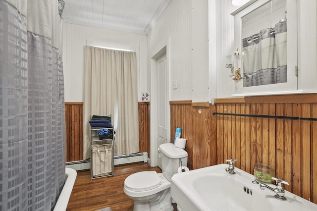 bathroom with a baseboard heating unit, a wainscoted wall, toilet, ornamental molding, and wood finished floors