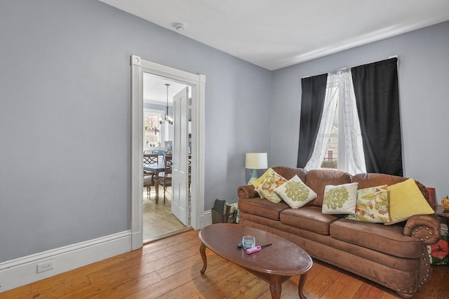 living room with hardwood / wood-style flooring, baseboards, and a chandelier