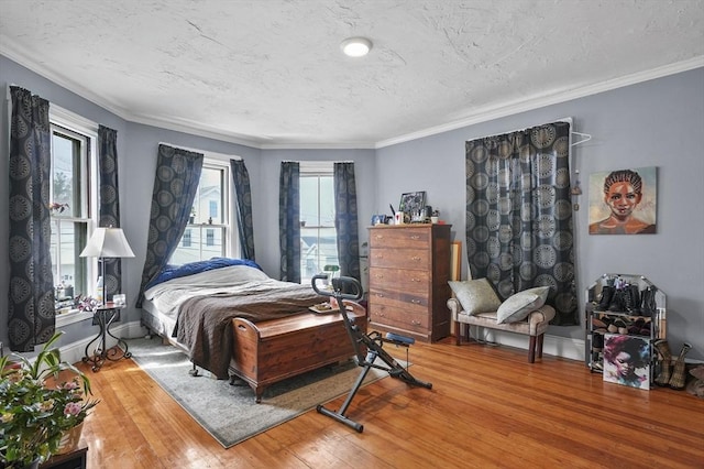 bedroom with baseboards, a textured ceiling, hardwood / wood-style floors, and ornamental molding