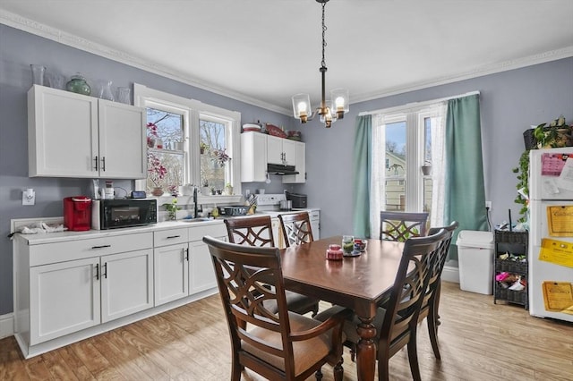 dining space featuring light wood-type flooring, a notable chandelier, and ornamental molding