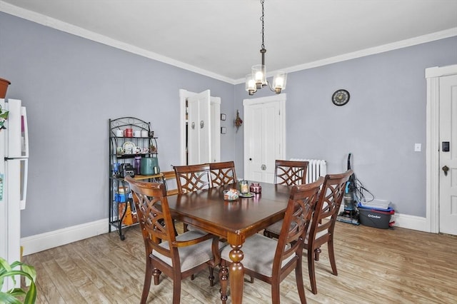 dining room with light wood finished floors, radiator, crown molding, and baseboards