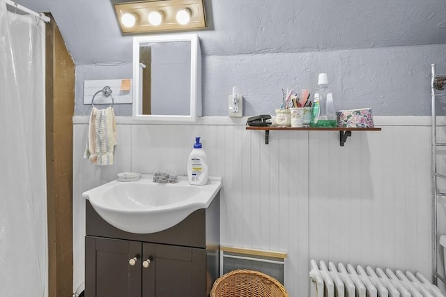 bathroom with vanity, radiator, and a textured wall