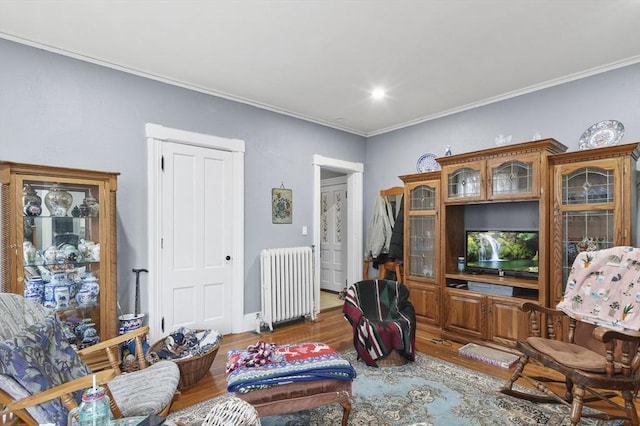 living area featuring wood finished floors, radiator heating unit, and ornamental molding