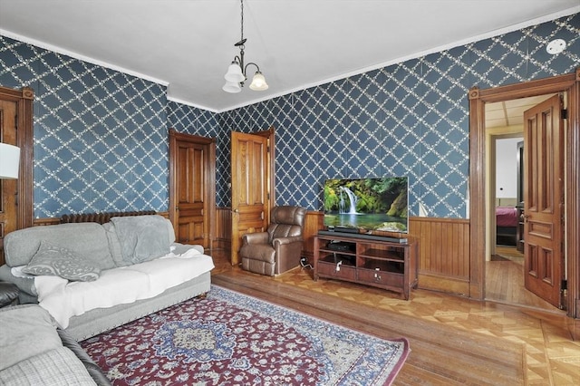 living room featuring wallpapered walls, an inviting chandelier, ornamental molding, wainscoting, and parquet floors