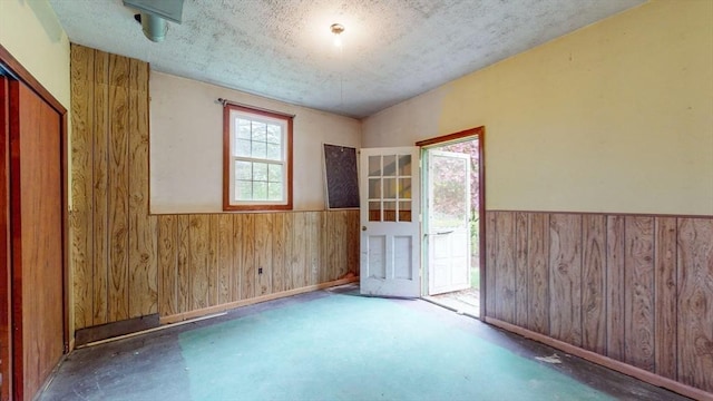 10 Briarwood Rd, Woburn, MA 01801 - unfurnished room with wood walls, wainscoting, concrete flooring, and a textured ceiling