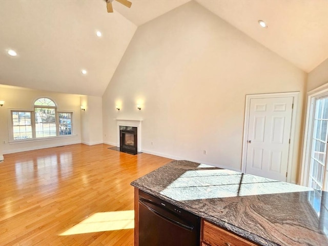 interior space with a high end fireplace, light wood-type flooring, ceiling fan, stone counters, and dishwasher