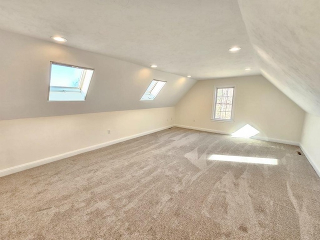 additional living space featuring carpet flooring and vaulted ceiling with skylight