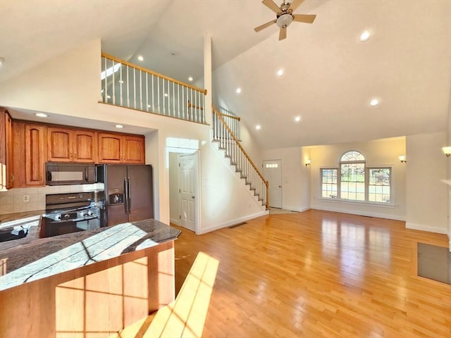 kitchen featuring stainless steel fridge, ceiling fan, high vaulted ceiling, range, and light hardwood / wood-style floors