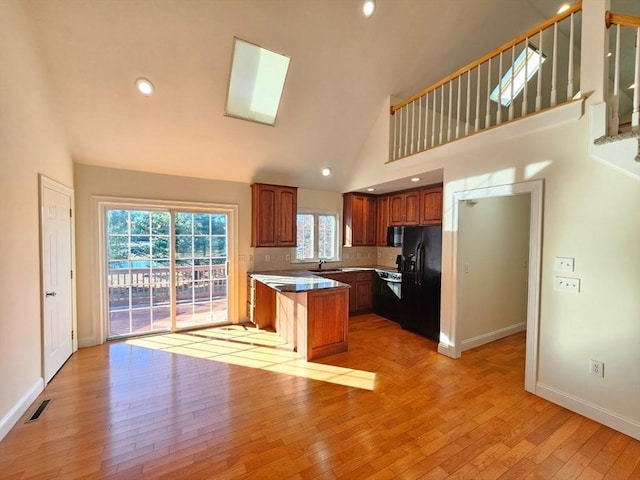 kitchen featuring decorative backsplash, black refrigerator with ice dispenser, light hardwood / wood-style flooring, and a kitchen island