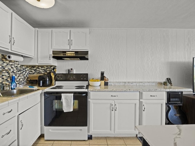 kitchen featuring a sink, under cabinet range hood, light tile patterned floors, white cabinets, and range with electric cooktop