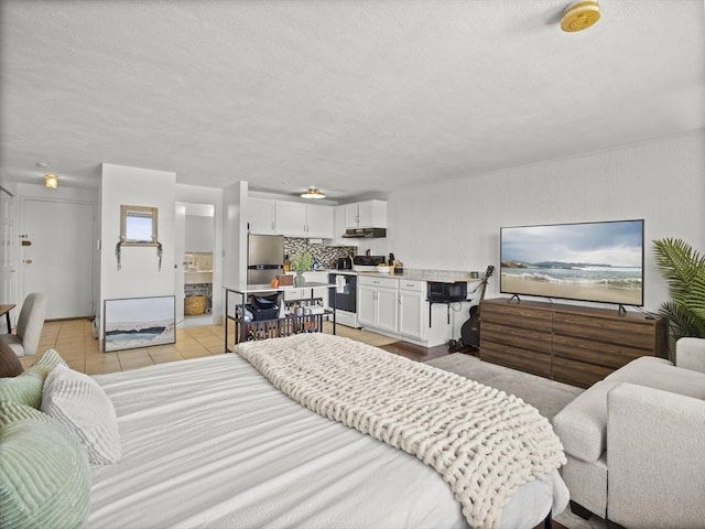 bedroom featuring freestanding refrigerator, light tile patterned floors, and a textured ceiling