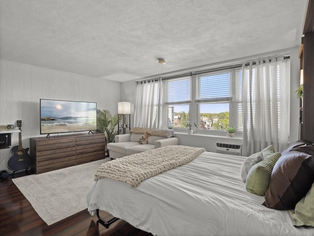 bedroom featuring an AC wall unit, a textured ceiling, and dark wood-type flooring