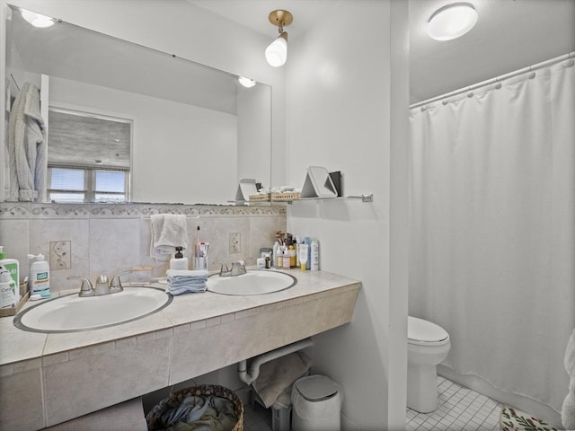 bathroom with double vanity, tile patterned floors, toilet, and a sink