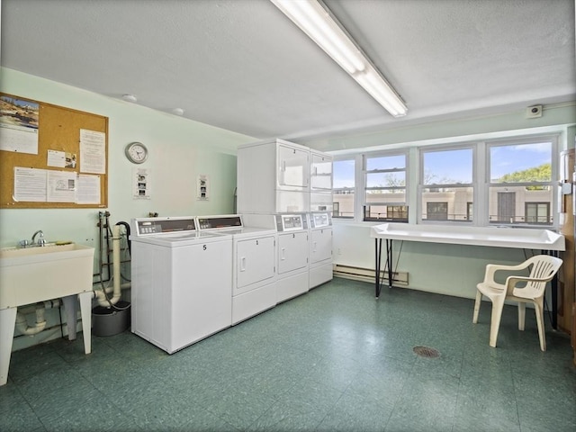 community laundry room with stacked washer / drying machine, a sink, washing machine and clothes dryer, tile patterned floors, and baseboard heating