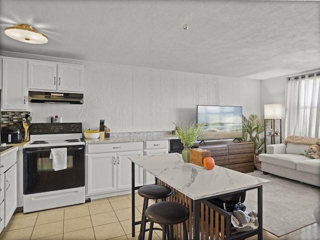 kitchen featuring under cabinet range hood, open floor plan, light tile patterned floors, white cabinets, and range with electric cooktop