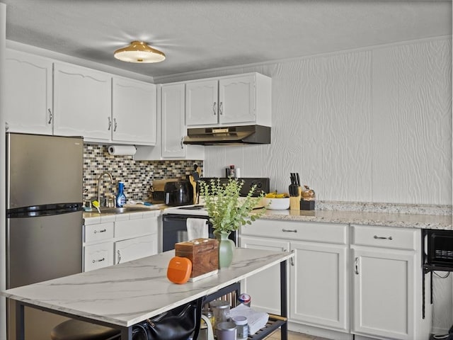 kitchen featuring under cabinet range hood, freestanding refrigerator, white cabinetry, and a sink