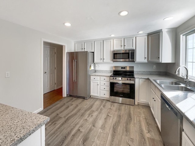 kitchen with recessed lighting, a sink, stainless steel appliances, light countertops, and light wood-style floors