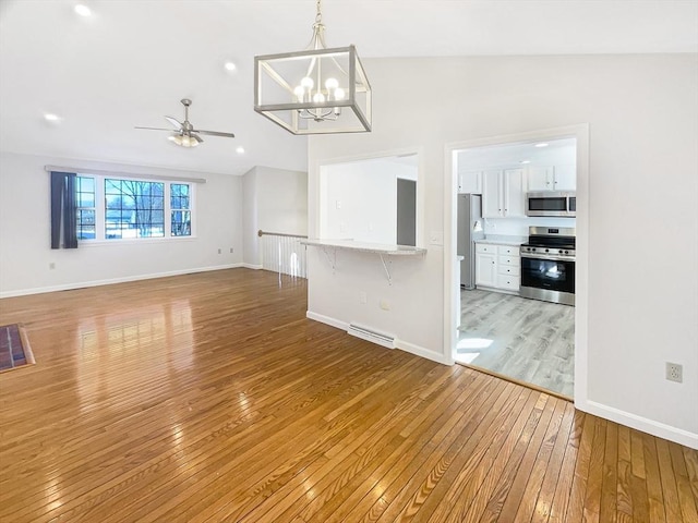 interior space with light wood-type flooring, visible vents, ceiling fan with notable chandelier, baseboards, and vaulted ceiling