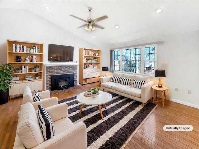 living room featuring baseboards, light wood-type flooring, lofted ceiling, recessed lighting, and a fireplace