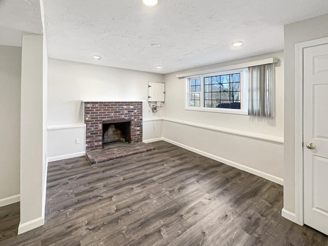 unfurnished living room with dark wood finished floors, a fireplace, baseboards, and a textured ceiling